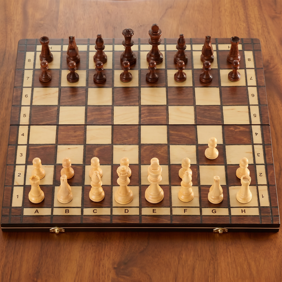Folding walnut chess board set up for play, seen at an angle